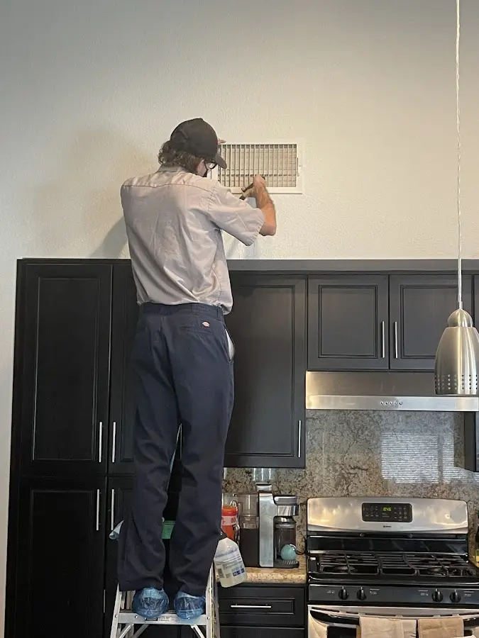 Technician inspecting an air vent during HVAC service in Lake Magdalene